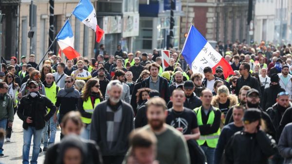 Demonstrators, some waving French national flags, walk in the streets of Rouen during a "Yellow Vests" protest on April 6, 2019 for the 21st consecutive Saturday. (KENZO TRIBOUILLARD / AFP) 