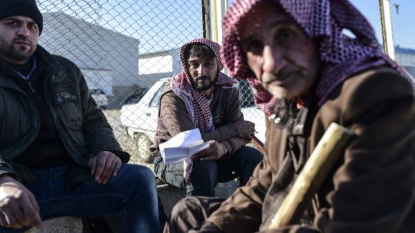 Syrian migrants and refugees wait in front of the Turkish Oncupinar crossing gate, near the town of Kilis, to return to Syria on February 9, 2016. (AFP/Bulent Kilis)
