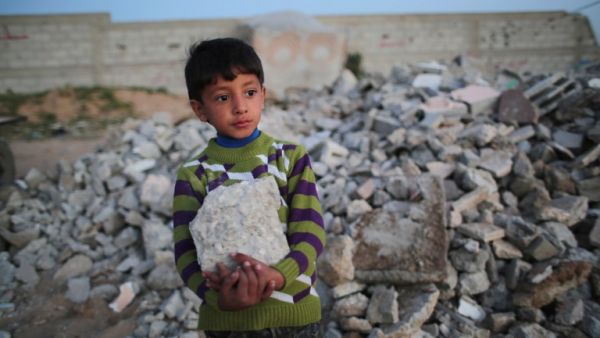 Palestinian Karim holds a rock as he helps his mother load it into their donkey-pulled cart in Khan Yunis in the southern Gaza Strip, on March 10, 2016. (AFP/Said Khatib)