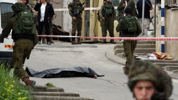 Israeli soldiers surround the body of one of the two Palestinians who were killed after wounding an Israeli soldier in a knife attack before being shot dead by troops in Hebron on March 24, 2016. (AFP/Hazem Bader)