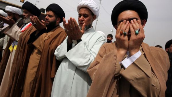 Shia clerics and supporters of Iraqi cleric Moqtada al-Sadr pray during a demo calling for governmental reform and elimination of corruption on March 25, 2016, outside the main gates of Baghdad's Green Zone. (AFP/Ahmad al-Ruvaye)