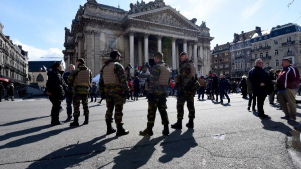 Belgian servicemen stand guard as people gather at the makeshift memorial on the Place de la Bourse Square, in Brussels, on March 27, 2016 to pay tribute to the victims of the Brussels terror attacks which killed 31 people and injured over 300. (AFP/Patrick Stollarz)