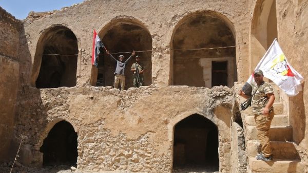 Fighters from the Hashed al-Shaabi (Popular Mobilisation units), backing the Iraqi forces, pose with the Iraqi flag from Tal Afar's Ottoman-era historic citadel after troops took control of the area during an operation to retake the city from the Islamic State (IS) group on August 27, 2017. Iraqi forces backed by local militia and a US-led coalition were poised to drive the Islamic State group from Tal Afar, dealing another blow to the jihadists. (AFP)