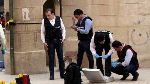 Egyptian security members and forensic police inspect the site of a gun attack outside a church south of the capital Cairo, on Dec. 29, 2017. A gunman opened fire on a church, killing at least nine people before policemen shot him dead, state media and officials said. 
(STRINGER / AFP)
