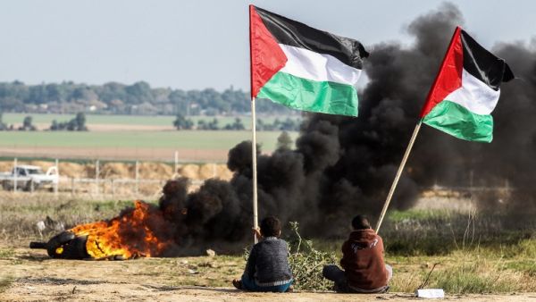 Palestinian protesters wave their national flag near the Israel-Gaza border east of the southern Gaza Strip city of Khan Yunis as they demonstrate against calls for the closure of UNRWA on Jan. 9, 2018 (SAID KHATIB / AFP)