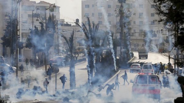 Palestinian protesters take cover from tear gas during clashes with Israeli forces on Jan. 12, 2018 north of Ramallah in the Israeli-occupied West Bank. 
ABBAS MOMANI / AFP