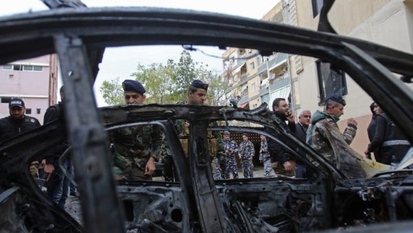 Lebanese security forces check a damaged vehicle following a car bomb blast in the southern Lebanese port city of Sidon on Jan. 14, 2018 (Mahmoud ZAYYAT / AFP)