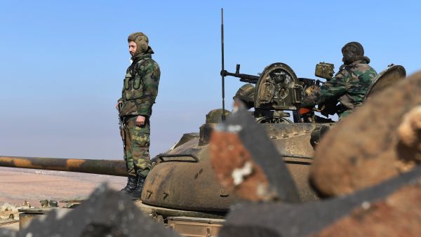 Members of the Syrian government forces stand on a tank in Jabal al-Hass in the southern part of Aleppo province as they advance towards the Abu Duhur military airport in the ongoing offensive against opposition fighters on January 14, 2018. Russia-backed regime troops are aiming to reach the Abu Duhur base as part of a weeks-long assault against Hayat Tahrir al-Sham (HTS), which is dominated by Al-Qaeda's former Syria affiliate. 