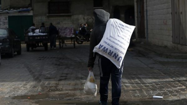 A Palestinian youth carries food donations outside the United Nations food distribution center in Gaza City on Jan. 15, 2018 (MOHAMMED ABED / AFP)