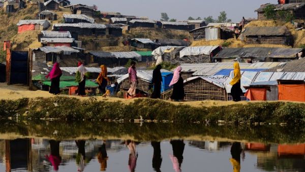 This file photo taken on Nov. 22, 2017 shows Rohingya refugees are reflected on a pond as they walk back to their homes at Balukhali refugee camp in the Bangladeshi district of Ukhia (MUNIR UZ ZAMAN / AFP)