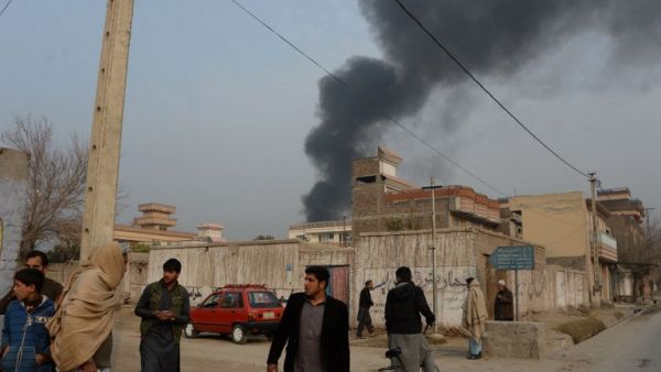 Afghan civilians gather on a street next to a plume of smoke coming from the area around an office of the British charity Save the Children during an ongoing attack in Jalalabad on Jan. 24, 2018 (NOORULLAH SHIRZADA / AFP)