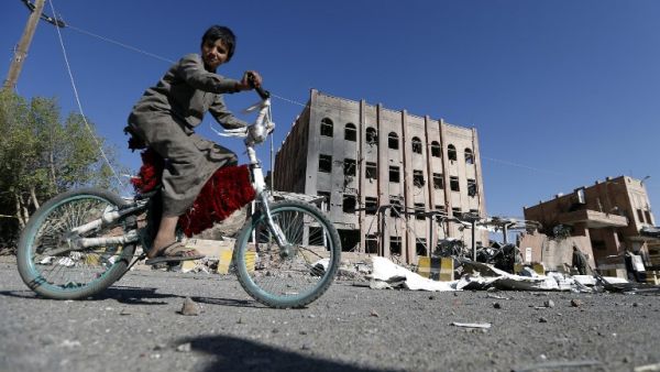 A picture taken on Feb. 5, 2018, shows a child riding his bike next to the Yemeni criminal investigations unit in the capital Sanaa, a day after it was hit in an air raid (MOHAMMED HUWAIS / AFP)