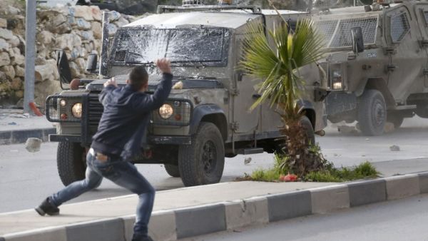 Palestinians throw stones at Israeli army vehicles after forces entered the village of Halhoul in the occupied West Bank on Feb. 07, 2018. A Palestinian stabbed a security guard at the entrance to an Israeli settlement and was shot dead in the latest violence in the occupied West Bank, Israel's military said.
(HAZEM BADER / AFP)