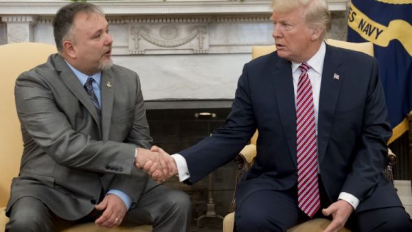 U.S. President Donald Trump shakes hands with Donald Bouvet (L), the father of a Trump presidential campaign volunteer who received a check for $10,000 from Trump with the money being used to treat Bouvet's bladder cancer, during a meeting in the Oval Office of the White House in Washington, DC, Feb. 9, 2018. 
(SAUL LOEB / AFP)