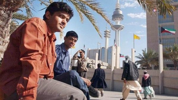 Asian workers take a break after work at a park next to Kuwait's Liberation Tower (AFP/File Photo)