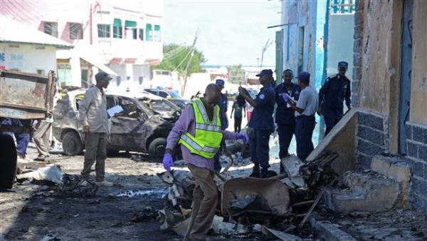 Somali soldiers and investigators work at the site of an explosion outside a restaurant in Mogadishu on April 9, 2016 (AFP)