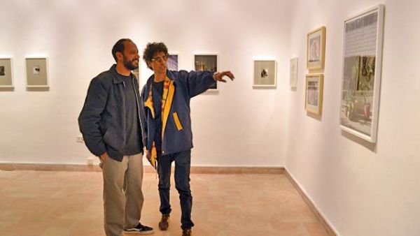 In this photo taken on Saturday, Mohammed Zakaria (left) and a viewer examine one of Zakaria’s photos at the Image Festival Amman (Photo by Yasmeen Kanaan)