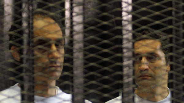 Alaa (R) and Gamal Mubarak, sons of ousted Egyptian president Hosni Mubarak, standing inside a cage in a courtroom during their verdict hearing in Cairo. (AFP/File)