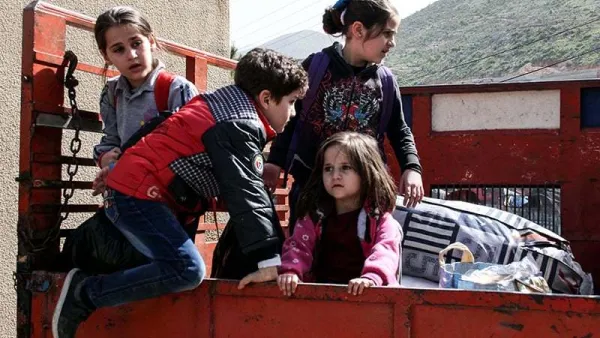 Syrian child refugees ride in the back of a pickup truck prior to their evacuation from Lebanon. (AFP/File)