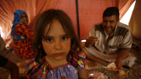 An Iraqi family poses for a photo in a tent at a makeshift camp for internally displaced persons (AFP/File Photo)