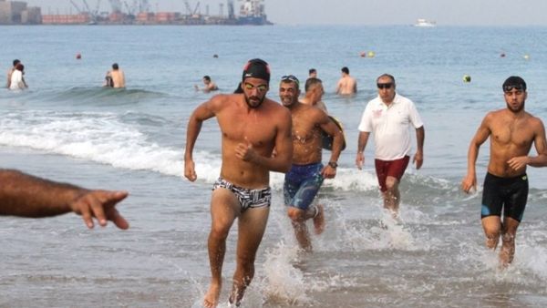 Triathlon participants emerge from the water after swimming 1,500 meters. (The Daily Star)