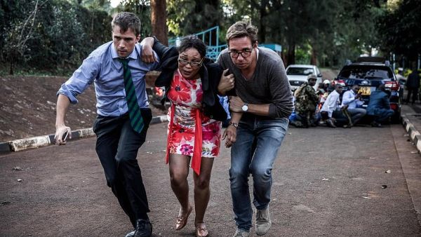 A woman is evacuated from the the hotel by two men during the terror attack on Tuesday afternoon which saw 21 civilians killed by the group of men linked to Al-Shabaab (AFP)