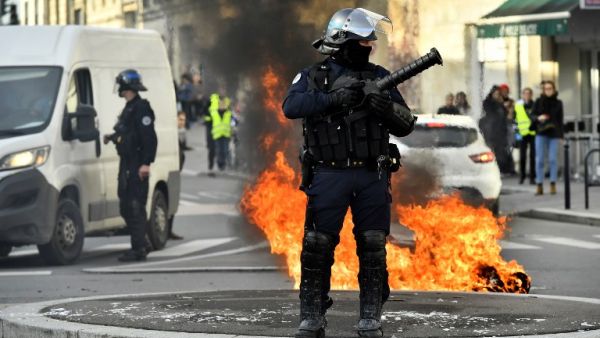A French riot police officer stands next to a burning barricade during a demonstration against French government Education reforms on December 5, 2018 in Bordeaux, southwestern France. 
NICOLAS TUCAT / AFP