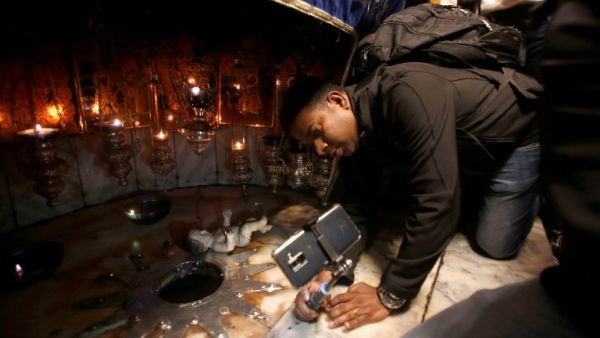 A man takes a selfie picture as tourists and pilgrims visit the Grotto, believed to be the exact spot where Jesus Christ was born, at the Church of the Nativity in the biblical West Bank city of Bethlehem, Musa AL SHAER / AFP
