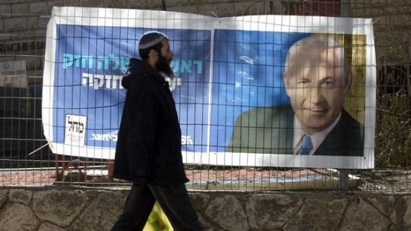 An Israeli settler walks past campaign posters of Israeli Prime Minister Binyamin Netanyahu at the Kiryat Arba settlement, in the Israeli occupied West Bank. (AFP PHOTO/MENAHEM KAHANA)