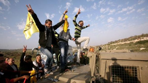 Palestinian protestors climb an Israeli military vehicle during a protest in Anin village in the West Bank near Jenin city. (AFP PHOTO/SAIF DAHLAH)