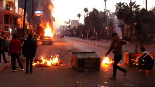 Egyptian anti-government protestors take cover behind burning dust bins during clashes with riot police. (AFP PHOTO / STR)