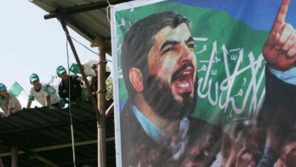 Palestinian supporters sit on the roof next to a poster of Hamas leader Khaled Meshaal. (Photo by Abid Katib/Getty Images)