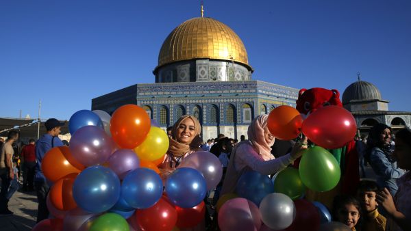 A Palestinian Woman Holding Balloons in front of the Dome of the Rock at Al Aqsa Mosque in Jerusalem. (AFP/ Ahmad Gharabli)