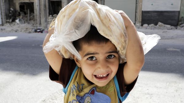 A Syrian boy carrying a bag of bread on his way home in Aleppo. (AFP/ Joseph Eid)
