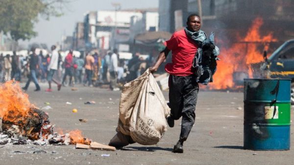 A street vendor flees with his goods as Zimbabwe opposition supporters clash with police in Harare. (AFP /Wilfred Kajese)