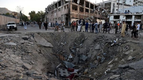 Afghan security forces and residents stand near the crater left by a truck bomb attack in Kabul on May 31, 2017. (AFP/Wakil Kohsar)