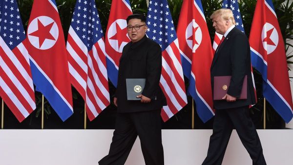 President Trump and North Korean leader Kim Jong Un carry their documents after the signing ceremony at the end of their summit. (AFP)