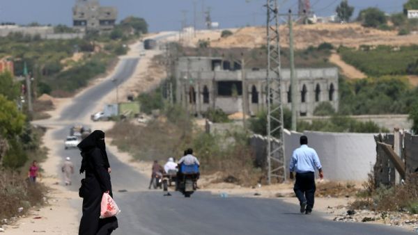 A Palestinian woman waits to be picked up on a road between the coast and the former Jewish settlement of Netzarim, south of Gaza City. (AFP/File) 