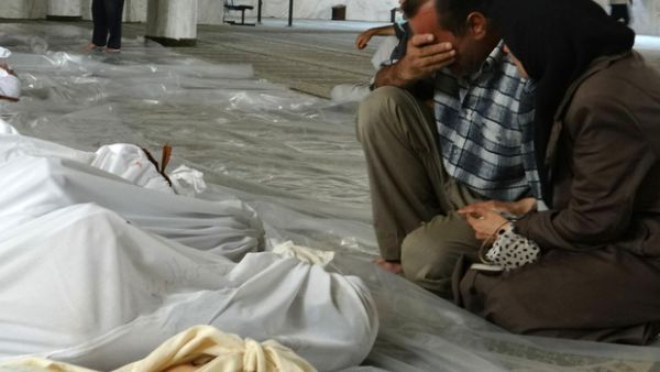 A handout image released by the Syrian opposition's Shaam News Network shows a Syrian couple mourning in front of bodies wrapped in shrouds ahead of funerals following what Syrian rebels claim to be a toxic gas attack by pro-government forces in eastern Ghouta. (AFP/File)