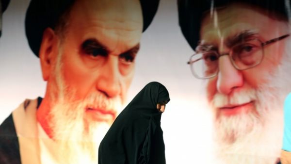 An Iranian woman walks past a giant poster showing supreme leader Ayatollah Ali Khamenei (R) and the founder of Iran's Islamic Republic, Ayatollah Ruhollah Khomeini (L), in Tehran. (AFP/File)