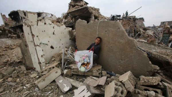 A Syrian boy sits with belongings he collected from the rubble of his house in Aleppo's Al-Arkoub neighborhood on December 17, 2016, after pro-government forces retook the area from rebel fighters. (AFP/Youssef Karwashan)