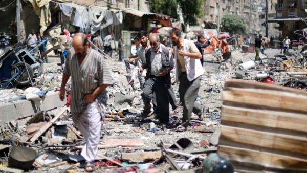Syrians walk amid the rubble following air strikes by Syrian government forces on a marketplace, east of the capital Damascus. (AFP/File) 