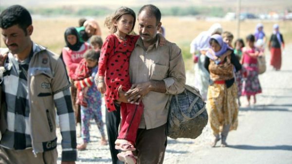 A displaced Iraqi man from the Yazidi community carries his daughter as they cross the Iraqi-Syrian border at the Fishkhabur crossing, in northern Iraq, on August 11, 2014. (AFP/Ahmad Al-Rubaye)