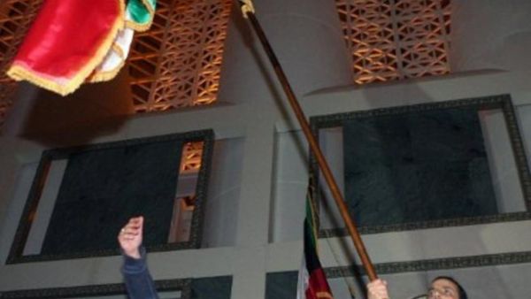 كويتيان يرفعان علم الكويت في مجلس الأمة.