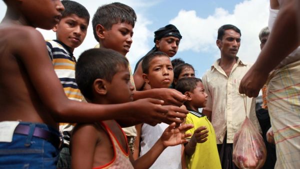 A Bangladeshi man distributes meat from a sacrificed animal to Rohingya refugees, during Eid al-Adha (AFP)