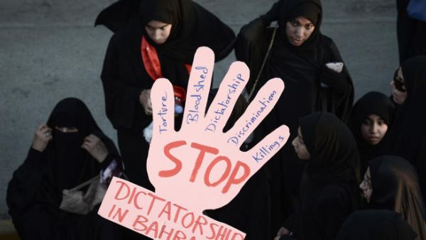 Bahraini women hold a placard reading 'Stop dictatorship in Bahrain' as they take part in an anti-government protest.(Image credit: AFP)