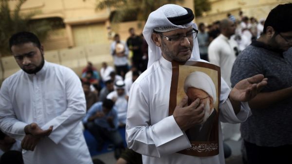 Bahraini protesters hold a placard bearing the portrait of top Bahraini Shia cleric Sheikh Issa Qassim, during a protest against the revocation of the clergyman’s citizenship, on June 20, 2016. (AFP/File)