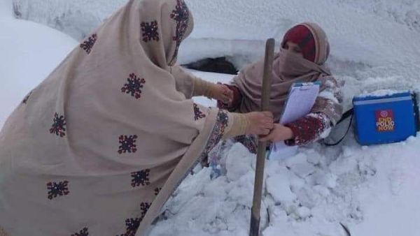 Two female polio vaccinators  trudge through waist high snow, somewhere in Pakistan (Twitter)