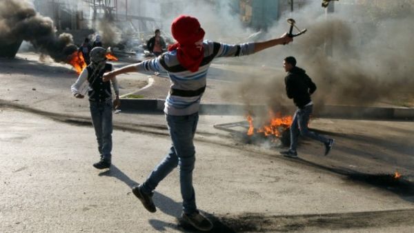 Palestinian protesters throw stones towards Israeli security forces during clashes in the West Bank city of Hebron on November 20, 2015. (AFP/Hazem Bader)