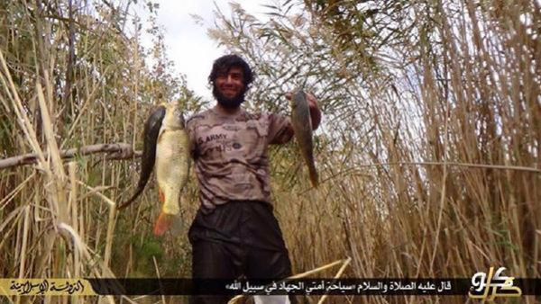 A Daesh militant shows off the fish he caught on a fishing trip. Note the U.S. Army logo on his shirt. (Twitter)